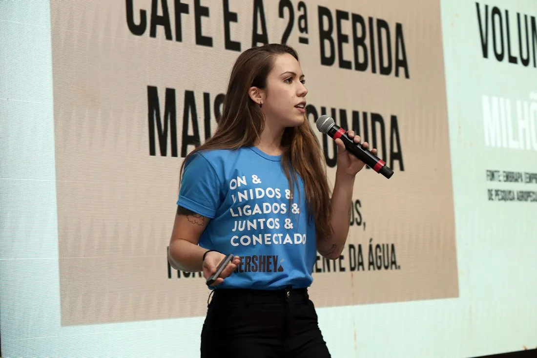 Larissa Reis apresentando no palco, com microfone